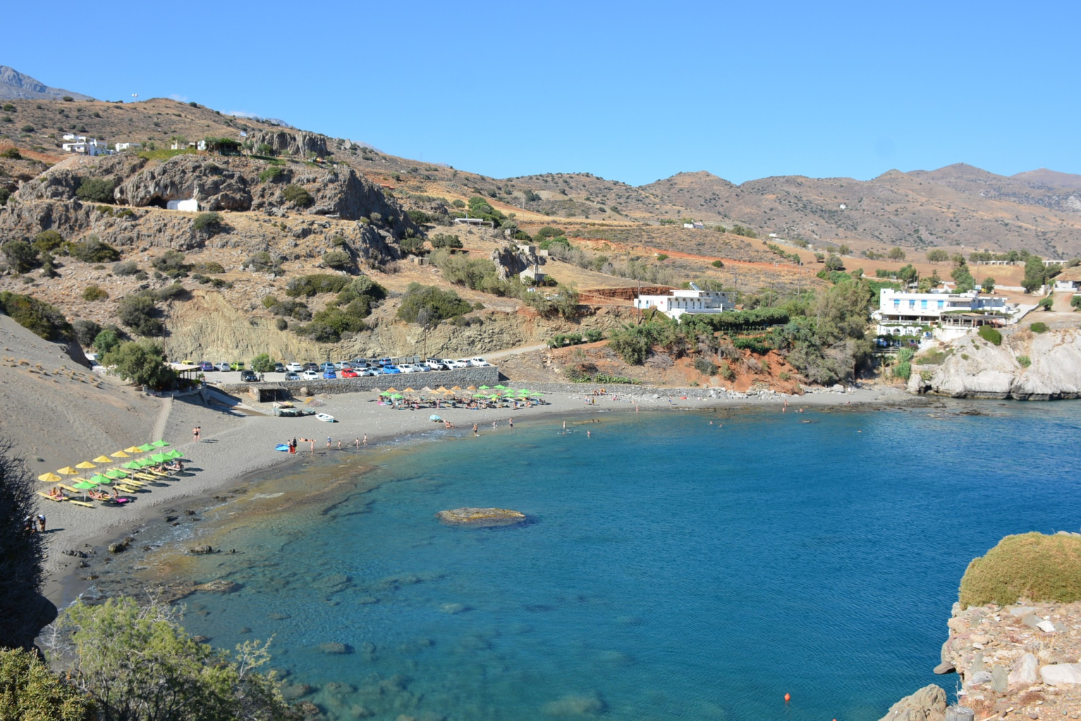 "Panoramic view of the unique Agios Pavlos sand dunes in South Rethymno, Crete, with crystal clear waters of the Libyan Sea and distant rugged mountains.