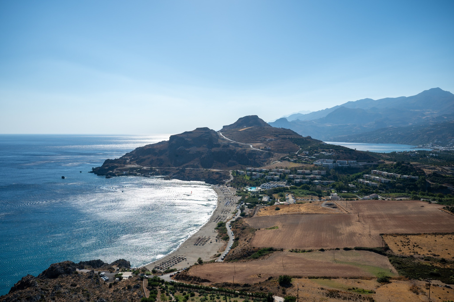 "The organized Damnoni beach in Rethymno, Crete, with sunbeds, umbrellas, and water sports center, ideal for family holidays."
